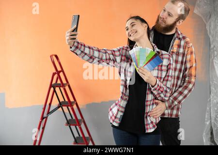 Heureux jeune couple rénover leur maison, peindre les murs et prendre un autoportrait utilise smartphone Banque D'Images