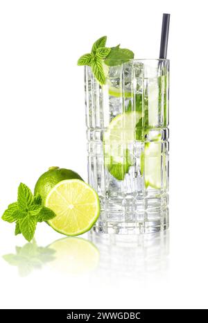 Cocktail Mojito dans un grand verre de cristal avec paille à boire, chaux et feuilles de menthe isolé sur une surface réfléchissante blanche. Banque D'Images