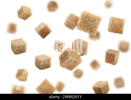 Cubes de sucre de canne brun tombant sur fond blanc Banque D'Images