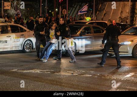 Tel Aviv, Israël. 23 mars 2024. Une israélienne portant un T-shirt « ramenez-les à la maison maintenant » traînée par des policiers pendant un barrage routier. Des milliers de manifestants contre le premier ministre Benjamin Netanyahu ont rejoint les familles israéliennes d'otages exigeant un accord immédiat d'otages, un cessez-le-feu et des élections générales dans l'État d'Israël. Des affrontements avec la police israélienne ont eu lieu après que des manifestants eurent allumé quelques feux de camp devant le quartier général des FDI et sur l'autoroute Ayalon, 15 ont été arrêtés. Crédit : SOPA images Limited/Alamy Live News Banque D'Images