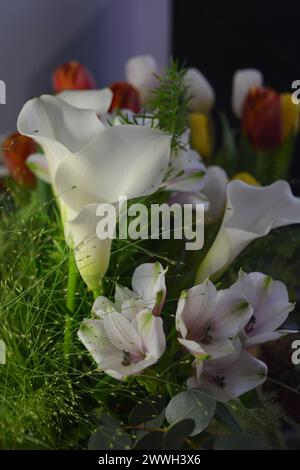 Bouquets lumineux et colorés de différentes fleurs de printemps. Beaux bouquets en bocaux, verres en verre, bouteilles posées sur une table en bois jaune. Banque D'Images