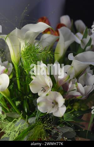 Bouquets lumineux et colorés de différentes fleurs de printemps. Beaux bouquets en bocaux, verres en verre, bouteilles posées sur une table en bois jaune. Banque D'Images