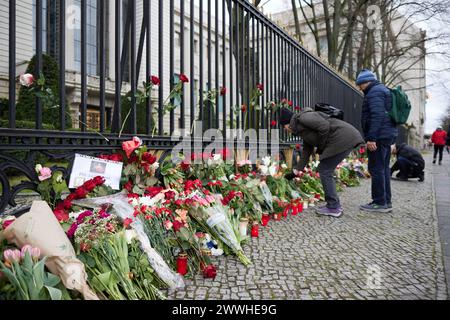 Berlin, Allemagne. 24 mars 2024. Les personnes en deuil déposent des fleurs à la clôture de l'ambassade russe. Selon les enquêteurs, le nombre de personnes tuées dans l'attaque terroriste contre le centre d'événements de l'hôtel de ville de Crocus à la périphérie de Moscou a augmenté à plus de 130. Crédit : Jörg Carstensen/dpa/Alamy Live News Banque D'Images