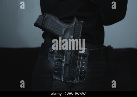 La fille a un pistolet dans un étui transparent sur une ceinture sur sa ceinture, photo en gros plan. Banque D'Images