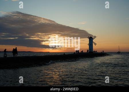 Moulin à vent à l'ancienne sur la jetée rocheuse sur la côte de l'île d'usedom le long de la mer baltique de Pologne avec beau coucher de soleil romantique et spectaculaire Banque D'Images