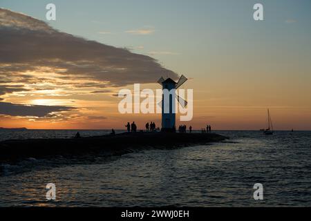 Moulin à vent à l'ancienne sur la jetée rocheuse sur la côte de l'île d'usedom le long de la mer baltique de Pologne avec beau coucher de soleil romantique et spectaculaire Banque D'Images