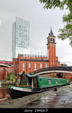 Bateau étroit aux couleurs vives amarré à Castlefield Basin sur le canal Bridgewater avec la Beetham Tower à Manchester, Angleterre, Royaume-Uni, Grande-Bretagne Banque D'Images