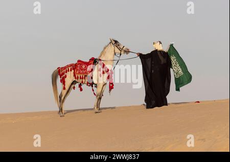 Homme saoudien en vêtements traditionnels avec son étalon blanc Banque D'Images