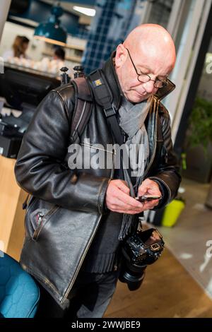 Photographe avec smartphone Rotterdam, pays-Bas. Calvitie, photographe d'âge moyen consultant son smartphone pour des messages. MRYES Rotterdam Bibliotheek, Blaak Zuid-Holland Nederland Copyright : xGuidoxKoppesx Banque D'Images