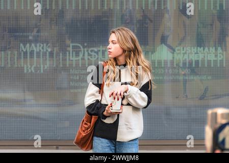 Portrait de rue captivant : jeune femme avec un café, jetant un regard sur son épaule. Banque D'Images