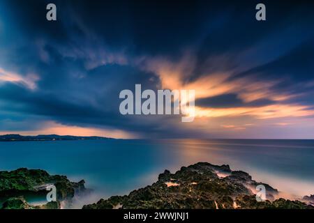 Le crépuscule tombe sur une plage rocheuse tropicale Banque D'Images