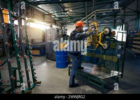 Foreman en gants de protection travaille dans un atelier de production de fenêtres Banque D'Images