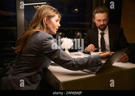 Femme d'affaires élégante ayant dîner dans un restaurant confortable avec partenaire d'affaires Banque D'Images