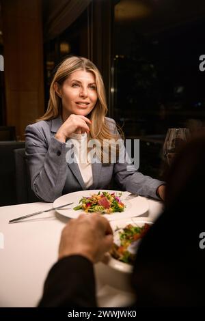 Belle femme d'affaires ayant dîner dans un restaurant confortable avec partenaire d'affaires Banque D'Images