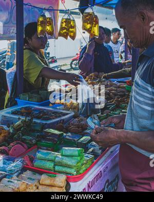 Balikpapan, Indonésie - 22 mars 2024. le vendeur remet la nourriture, tandis que l'homme compte l'argent en premier. Banque D'Images