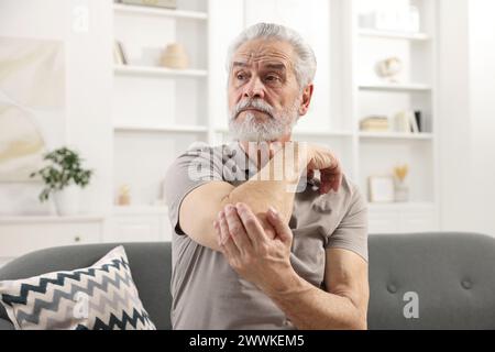 Symptômes de l'arthrite. Homme souffrant de douleurs au coude à la maison Banque D'Images