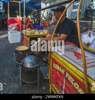 Balikpapan, Indonésie - 22 mars 2024. Il vend Kerak Telor snack au marché du Ramadan. Banque D'Images