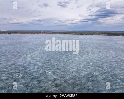 Vue aérienne de haut en bas de glace fissurée, brisée et fondante à la surface de l'eau. Fond de glace, lac gelé ou rivière recouvert de glace. Banque D'Images