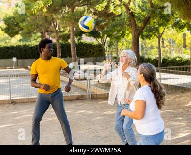 Club social de joyeux personnes âgées diverses appréciant le volley-ball le jour ensoleillé d'octobre plein air Banque D'Images