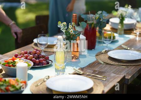 Gros plan de la table de préparation à la fête d'été, grillades. Table avec verres, limonade, délicate décoration florale et papier, et Banque D'Images