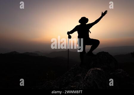 Grimpeur succès, silhouette réalisations réussi ARM Up Man est au sommet de la colline célébrant le succès avec le lever du soleil. Banque D'Images