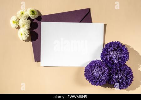 Belles petites fleurs violettes sur enveloppe bleue postale sur fond beige, espace de copie de note de papier vide pour le texte, printemps, carte de voeux pour les vacances. Concept de livraison de fleurs Banque D'Images