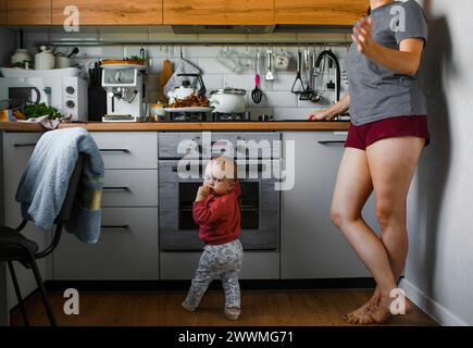 L'enfant est debout dans la cuisine à côté de sa mère Banque D'Images