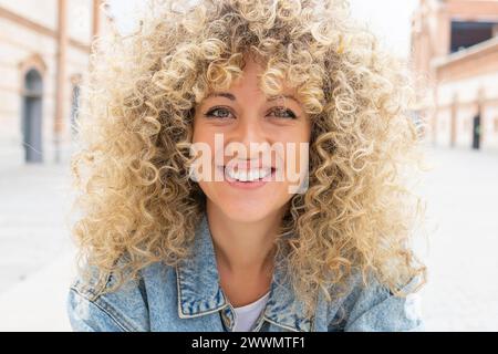 Portrait d'une jeune femme caucasienne souriante aux cheveux blonds bouclés Banque D'Images