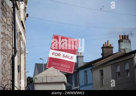 H Sowen agent immobilier rouge et blanc pour la vente signe à l'extérieur de la rue avec des maisons mitoyennes contre un ciel bleu Banque D'Images