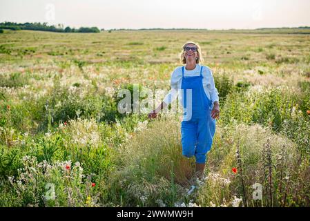 fröhliche Junge Frau mit Sonnenbrille im Mohnfeld *** jeune femme joyeuse avec des lunettes de soleil dans un champ de coquelicots Banque D'Images