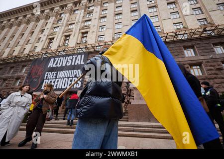 Jeune fille marche avec un grand drapeau de l'Ukraine sur un rassemblement public. Kiev - 23 mars 2024 Banque D'Images