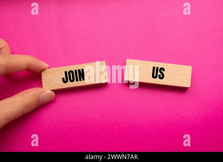 Rejoignez-nous des mots écrits sur des blocs de bois avec fond rose. Symbole commercial conceptuel. Copier l'espace. Banque D'Images