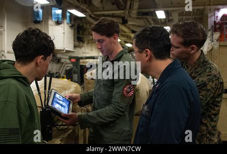 OCÉAN PACIFIQUE (17 février 2024) Sergent Joseph Dutcher, centre gauche, de East Bridgewater, Massachusetts, affecté au bataillon logistique de combat 31, élimination d'explosifs (EOD), 31st Marine Expeditionary Unit (MEU), montre comment contrôler une plate-forme robotique lors d'une démonstration d'élimination d'explosifs (EOD) dans la zone de stockage de véhicules du porte-avions d'assaut amphibie déployé à l'avant USS America (LHA 6), tout en menant des opérations de routine dans l'océan Pacifique, le 17 février. America, navire principal de l'America Amphibious Ready Group, opère dans la zone de la 7e flotte américaine Banque D'Images