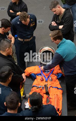 Des marins de l'US Navy affectés à la Fleet Surgical Team 3 et aux affiliés de la NASA inspectent la combinaison d'entraînement Orion Crew Survival Systems dans la baie du hangar à bord du navire de transport amphibie de classe San Antonio USS San Diego (LPD 22) pendant le test de récupération en cours 11, le 22 février 2024. En préparation de la mission Artemis II avec équipage de la NASA, qui enverra quatre astronautes à Orion au-delà de la Lune, la NASA et le ministère de la Défense mèneront une série de tests pour démontrer et évaluer les processus, les procédures et le matériel utilisés dans les opérations de récupération pour les missions lunaires avec équipage. L'US Navy a beaucoup d'uniqu Banque D'Images