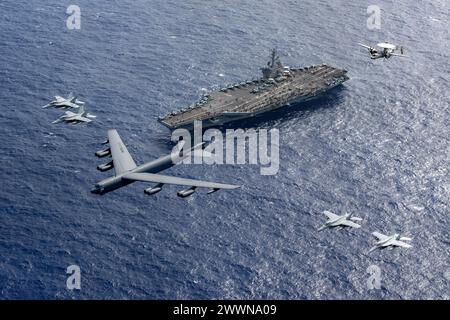 PHILIPPINE SEA (24 février 2024) Un B-52 Stratofortress de l'US Air Force, attaché à la 5th Bomb Wing, et des avions attachés à la Carrier Air Wing (CVW) 11, volent en formation au-dessus du porte-avions de classe Nimitz USS Theodore Roosevelt (CVN 71), 24 février 2024. Theodore Roosevelt, navire amiral du Carrier Strike Group Nine, mène des opérations de routine dans la zone d'opérations de la 7e flotte américaine. La 7e flotte américaine est la plus grande flotte numérotée déployée vers l’avant de l’US Navy. Elle interagit et opère régulièrement avec des alliés et des partenaires pour préserver une région indo-pacifique libre et ouverte. Marine Banque D'Images