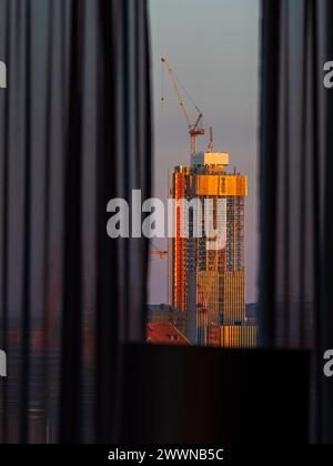 La lueur chaude du lever du soleil baigne un gratte-ciel en construction à Gothenburg, en Suède. Vue d'un point de vue intérieur, la silhouette des rideaux Banque D'Images