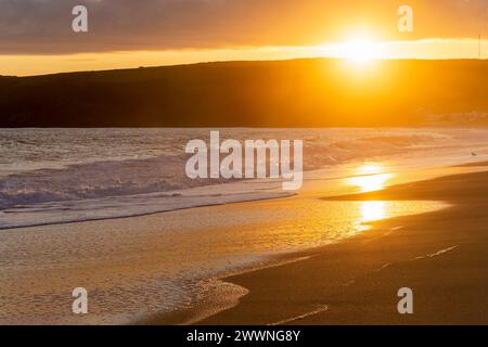 Lumière dorée du soir avec vue sur Praa Sands en Cornouailles vers Sydney Cove et Hoe point avec lumière dorée sur sable humide et vagues. Banque D'Images