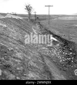 Locaux désordonnés d'une coopérative agricole d'État (C.A.P.) en Roumanie communiste, dans les années 1970 Grande quantité d'engrais laissée négligemment au bord d'une route, près d'un fossé. Banque D'Images