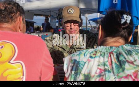 Jason Dunn, le chef principal des forces recrutées pour le commandant du Navy installations Command, qui supervise 70 bases navales à travers le monde, parle avec des résidents d’Hawaï du programme de surveillance à long terme de l’eau potable de la Marine lors d’un marché nocturne à Ewa Beach, Hawaï, le 14 février 2024. La Marine organise un kiosque d'information mensuel à divers endroits pour informer le public sur le programme et sur la façon de lire les résultats de l'eau potable sur le site Web de la base conjointe Pearl Harbor-Hickam Safe Waters. Dunn est l'un des nombreux chefs de la Navy qui se sont rendus à Hawaï pour soutenir la Navy Closure Task Forc Banque D'Images