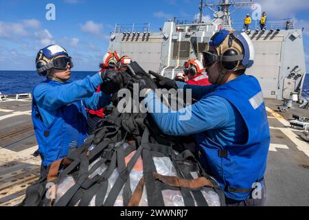 OCÉAN PACIFIQUE (17 février 2024) des marins déchargent une palette de fournitures lors d'un réapprovisionnement vertical sur le pont d'envol du destroyer de missiles guidés de classe Arleigh Burke USS Rafael Peralta (DDG 115) lors d'un réapprovisionnement en mer avec le navire de cargaison sèche et de munitions USNS Cesar Chavez (T-AKE 14). Cesar Chavez est affecté au Military Sealift Command Far East (MSC FE) qui, en coordination avec le commandant de la Task Force 73, ravitaille et ravitaille les forces navales déployées, ainsi que les alliés et partenaires régionaux dans l’Indo-Pacifique. Rafael Peralta est déployé en avant et affecté au commandant de la Force opérationnelle 7 Banque D'Images