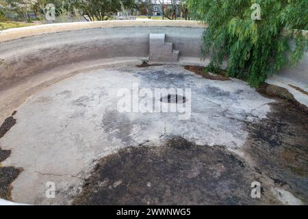 Partie d'une grande piscine ronde vide en béton. Au fond de la piscine il y a des fissures. Concept pour piscines qui fuient. Banque D'Images