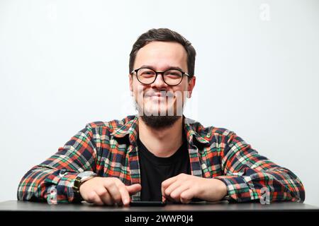 Portrait de jeune homme caucasien souriant sur fond blanc. Homme portant des lunettes, une montre et une chemise décontractée en denim, isolé sur blanc. Banque D'Images