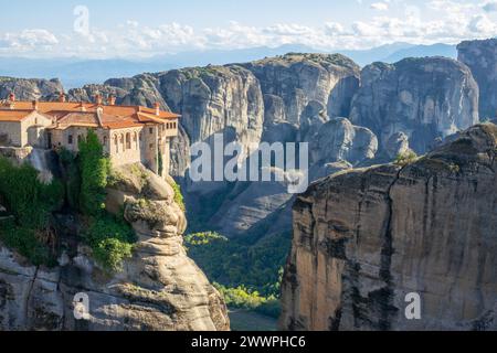 Grèce. Journée d'été ensoleillée à Kalambaka. Monastère rocheux aux toits rouges. Nuages légers dans le ciel bleu au-dessus de la chaîne de montagnes en arrière-plan Banque D'Images