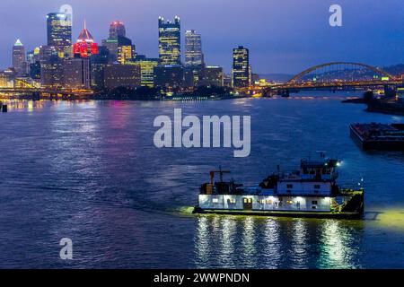 Un remorqueur navigue vers une zone de rassemblement pour les barges remplies de charbon et d'autres produits sur la rivière Ohio à Pittsburgh avant le lever du soleil, le 2 février 2024. Le district de Pittsburgh du corps of Engineers des États-Unis est connu sous le nom de «Headwaters District» parce que le point de la ville est l'endroit où les rivières Allegheny et Monongahela convergent pour former la rivière Ohio, qui relie la région à de nombreuses voies navigables intérieures pour le reste du pays. Le district gère les cours d'eau et les bassins versants qui coulent dans des parties importantes du nord-est des États-Unis. Le district exploite 23 écluses et barrages, Banque D'Images