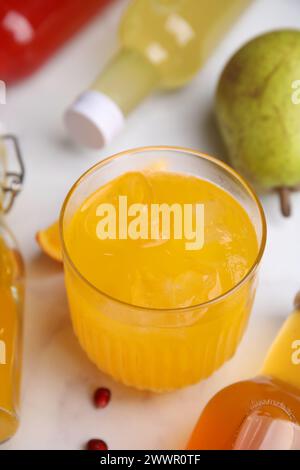 Savoureux kombucha en verre et bouteilles sur table blanche, gros plan Banque D'Images