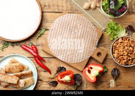 Papier de riz, ingrédients et savoureux rouleaux de printemps frits sur table en bois, plat Banque D'Images