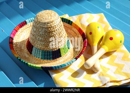 Chapeau sombrero mexicain, serviette et maracas sur surface en bois bleu Banque D'Images