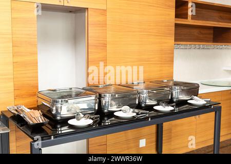 Rangée de plats buffet fermés dans la salle de banquet. Plat à frotter prêt pour le service en acier inoxydable au buffet. Banque D'Images