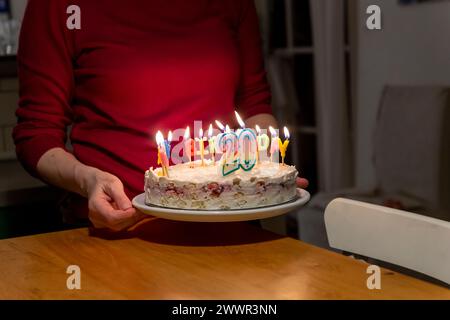 mains avec allumettes allumant des bougies vax sur le gâteau d'anniversaire Banque D'Images