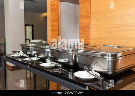 Rangée de plats buffet fermés dans la salle de banquet. Plat à frotter prêt pour le service en acier inoxydable au buffet. Banque D'Images